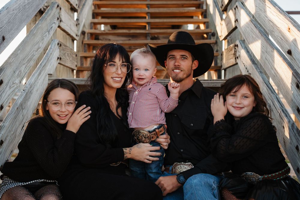 Happy family of five posing together on wooden stairs outdoors.
