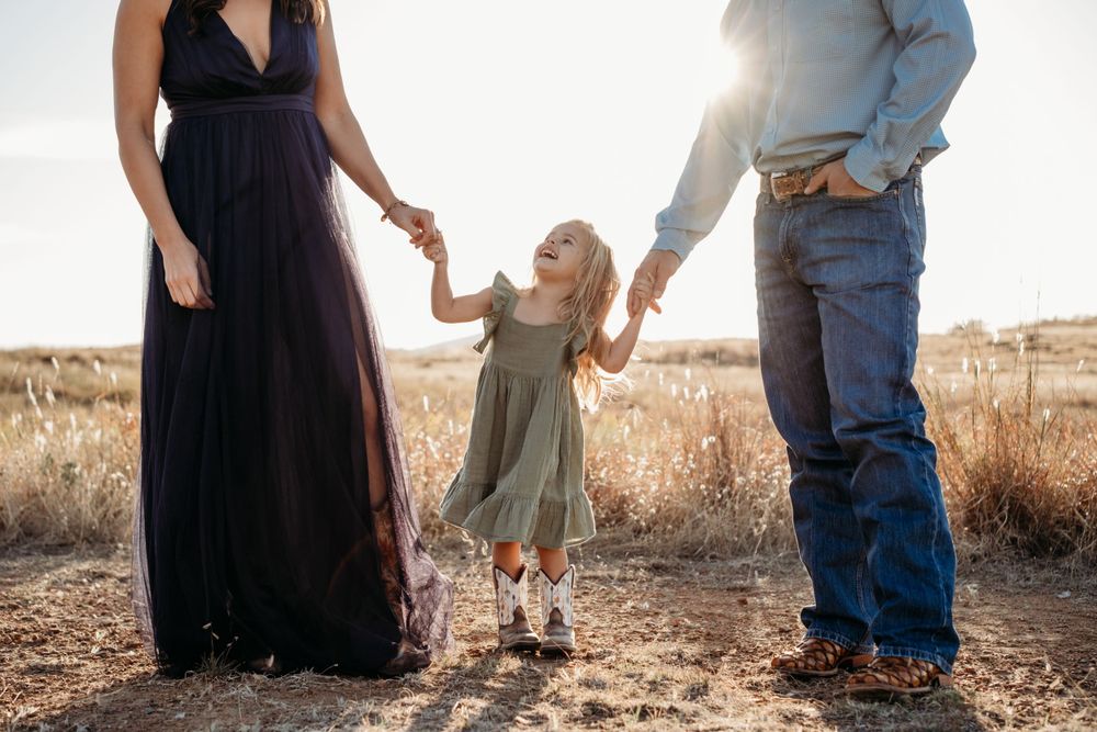 A family in casual clothing stands together against a golden sunlit backdrop.