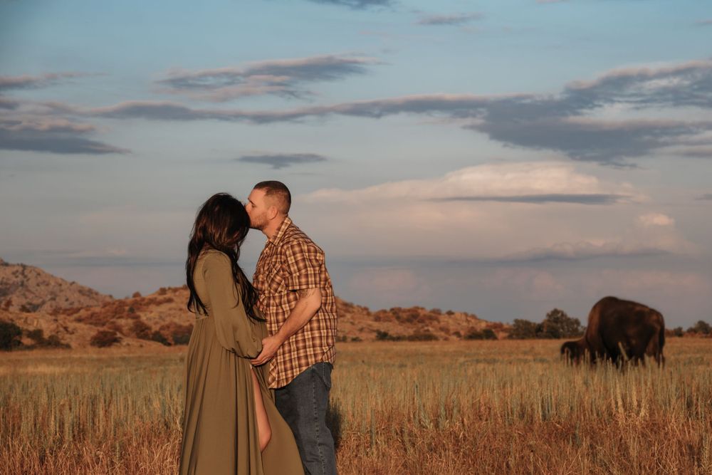 Romantic sunset moment with couple in countryside field with buffalo in background.
