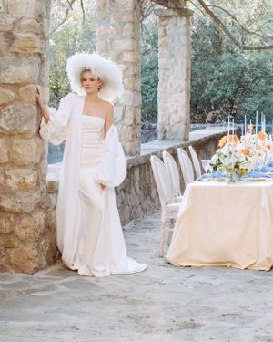 Fashion forward bride in a long white dress with feather hat. Destination wedding Barcelona. Barcelona Photographer
