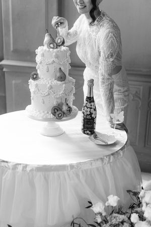 Wedding cake table with champagne bottle and bride cutting the cake. Schloss Schadau Swiss wedding photographer. Schweizer Hochzeitsfotograf