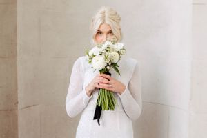 Bride with her bridal bouquet with all white flowers & a black bow around the flowers. Zurich wedding photographer. Hochzeitfotograf Zürich