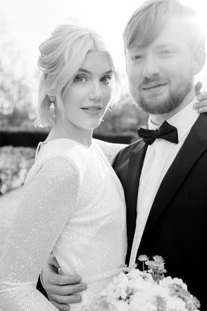 Bride and groom at their London town hall wedding. She is wearing a short white dress and he is wearing a dark smoking.