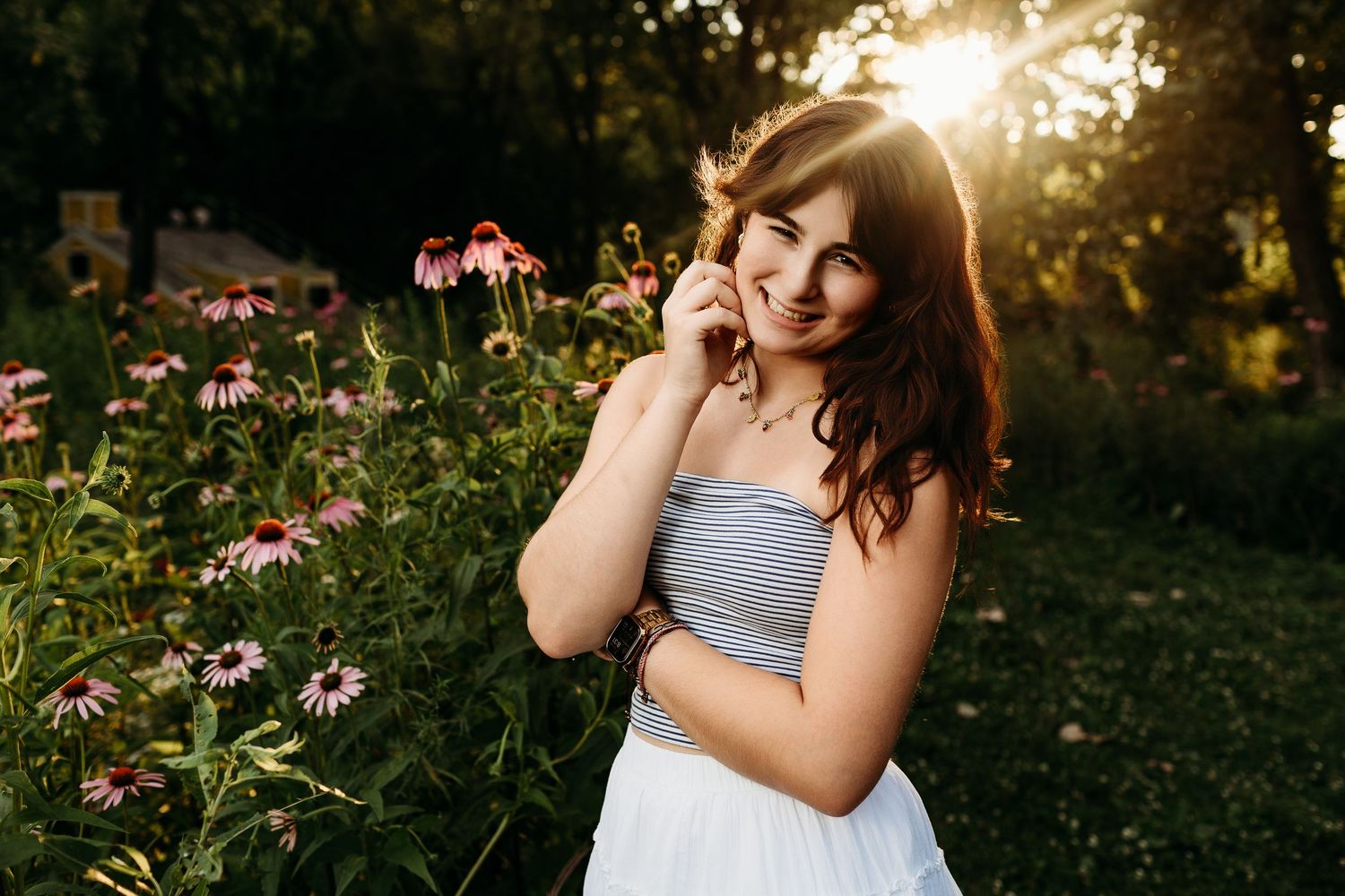 Woman in white dress spins joyfully in beautiful garden filled with pink and yellow blooming flowers.