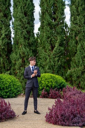 A series of playful poses against a backdrop of tall cypress trees and purple flowering bushes.