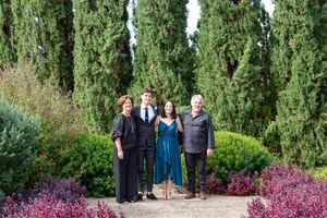 Group photo session with family members in front of cypress trees and purple foliage.