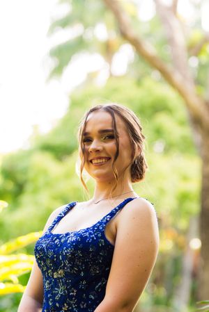 Woman in sparkling navy blue formal dress poses outdoors with natural lighting.
