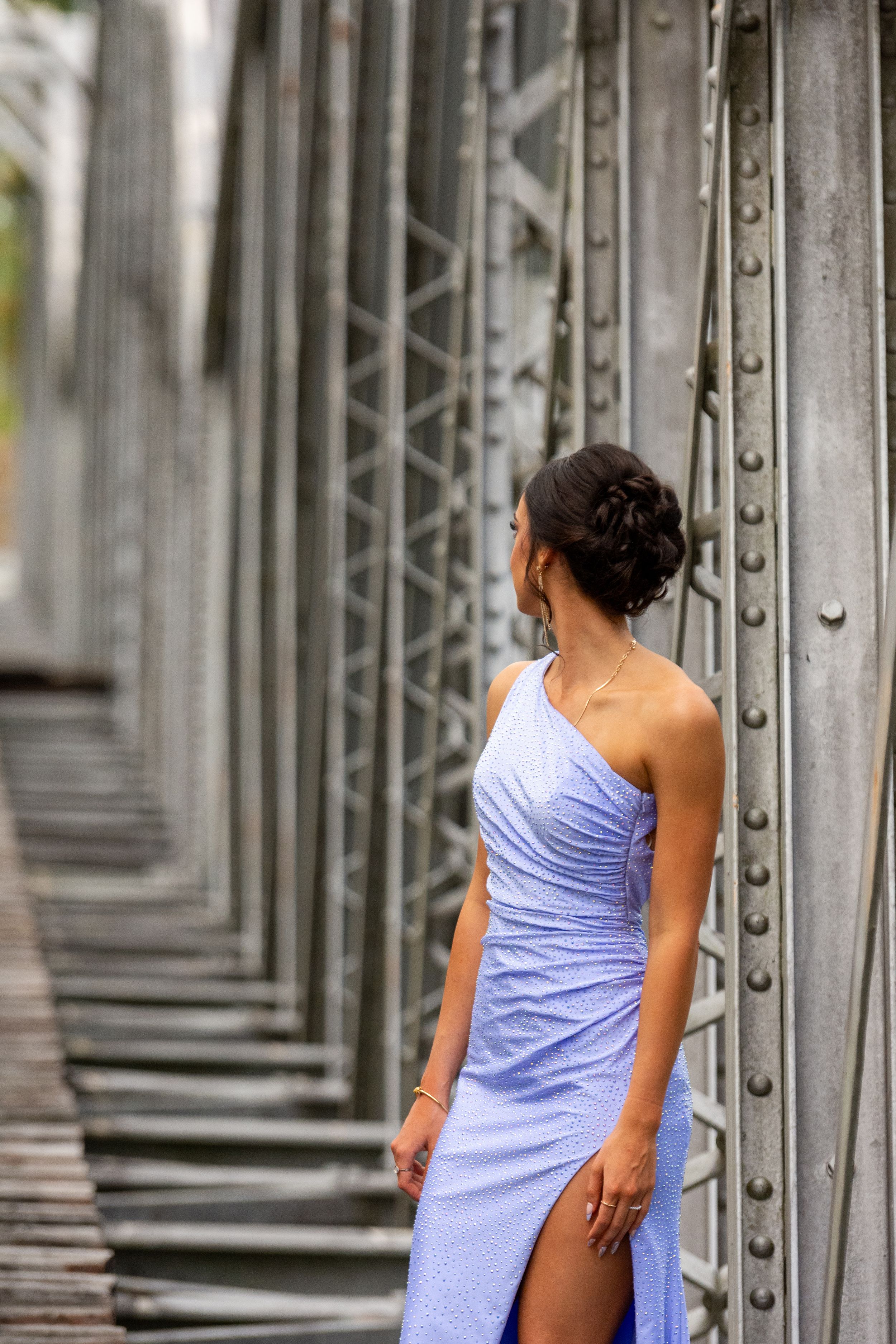 Fashion photo on industrial bridge with repeating metal framework patterns.