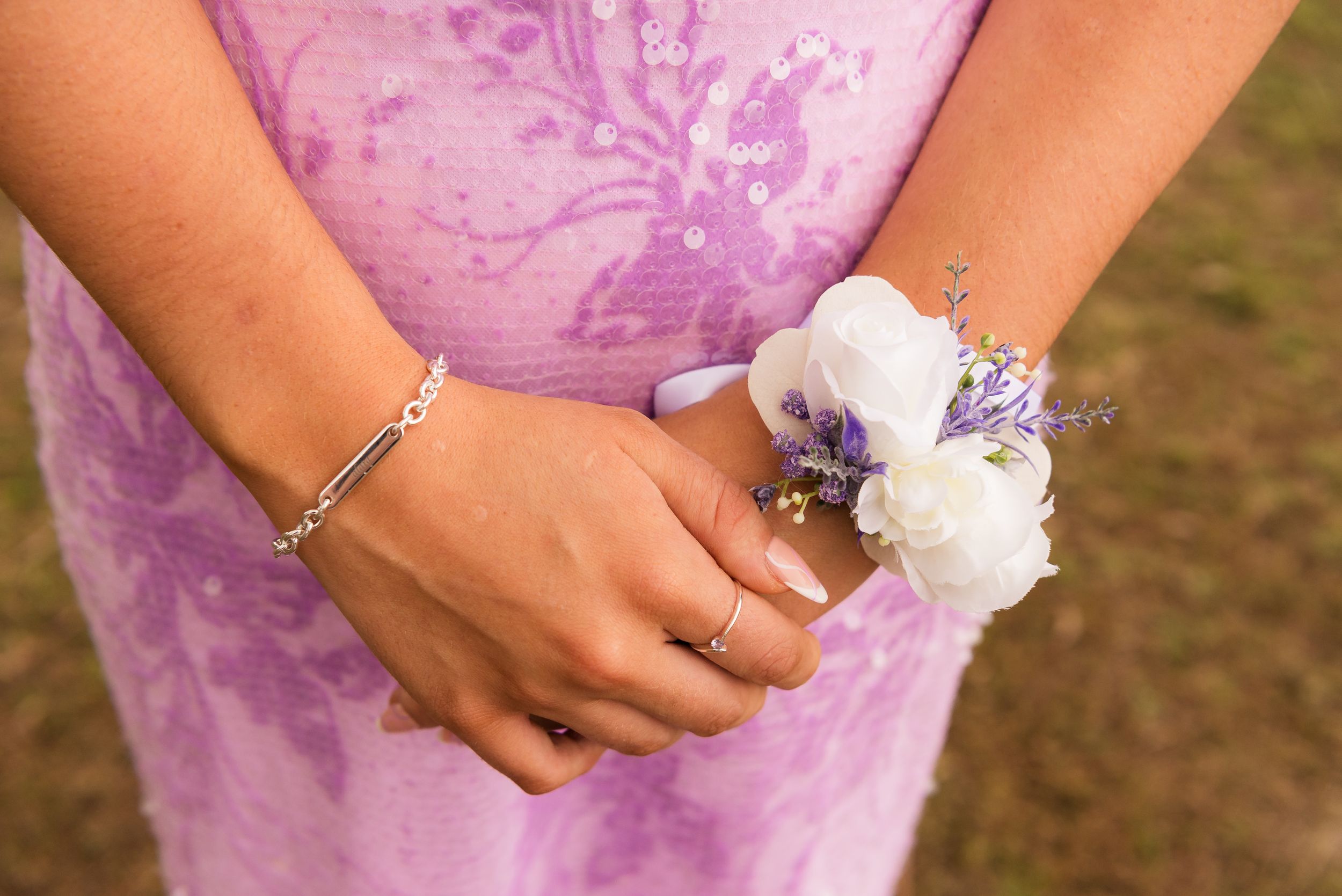 Close-up of hands wearing delicate bridal jewelry and rings.