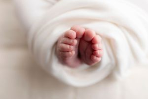 Close-up of tiny baby feet wrapped in soft white blanket.