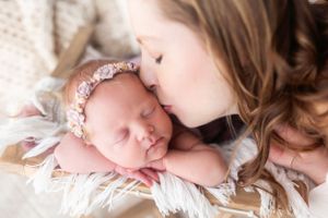 Gentle newborn portrait with soft white wrap and lace accents.