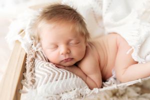 A sleeping newborn baby rests peacefully on chevron-patterned blankets.
