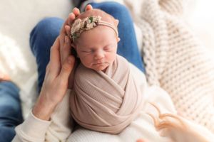 Serene newborn session with neutral wraps and delicate headpiece.