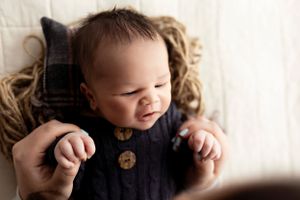 Soft portrait of sleeping newborn wrapped in neutral toned fabrics against white background.