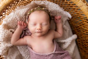 Sweet newborn portrait in neutral tones with delicate lace headband.