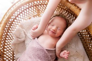 Peaceful sleeping newborn in wicker basket with cozy knit blankets.