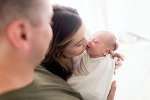 Tender moment between parents and newborn during lifestyle photo session.