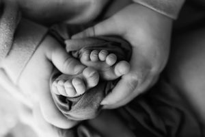 Series of minimalist black and white newborn photography poses showing gentle hand details.