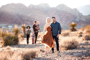 Group walking through desert landscape with red rock formations in background.