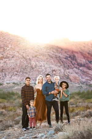 Family portrait in desert setting with red rock formations during sunset.