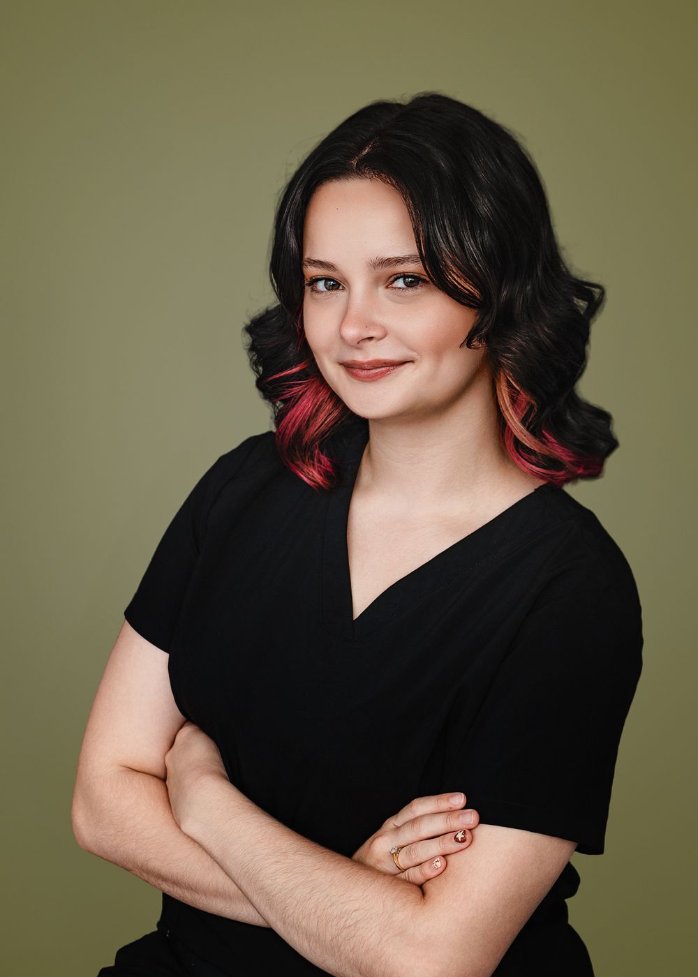 A series of headshots of someone with dark curly hair and red highlights wearing a black top against a green background.