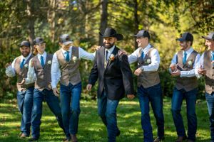 Groomsmen in casual attire with vests share a lighthearted moment outdoors.