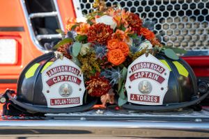 Two firefighter helmets decorated with fall flowers and wedding floral arrangements.