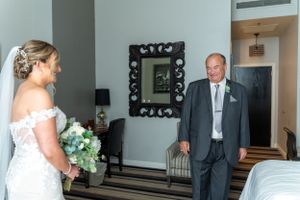 Emotional wedding day first look moment captured in a hotel room setting.