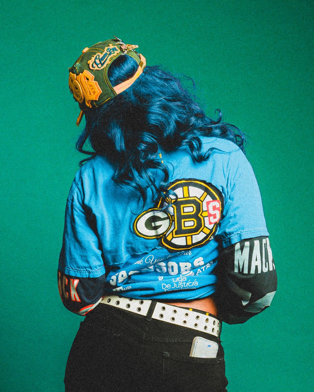 Stylish blue GB sports jacket and white studded belt shown against emerald green background.