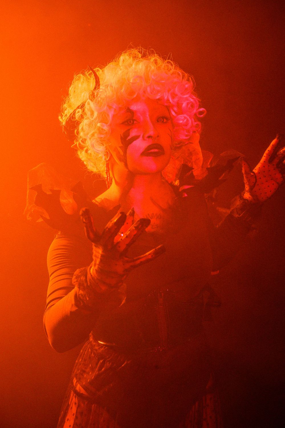 Theatrical performance shot with dramatic orange lighting and expressive gestures.