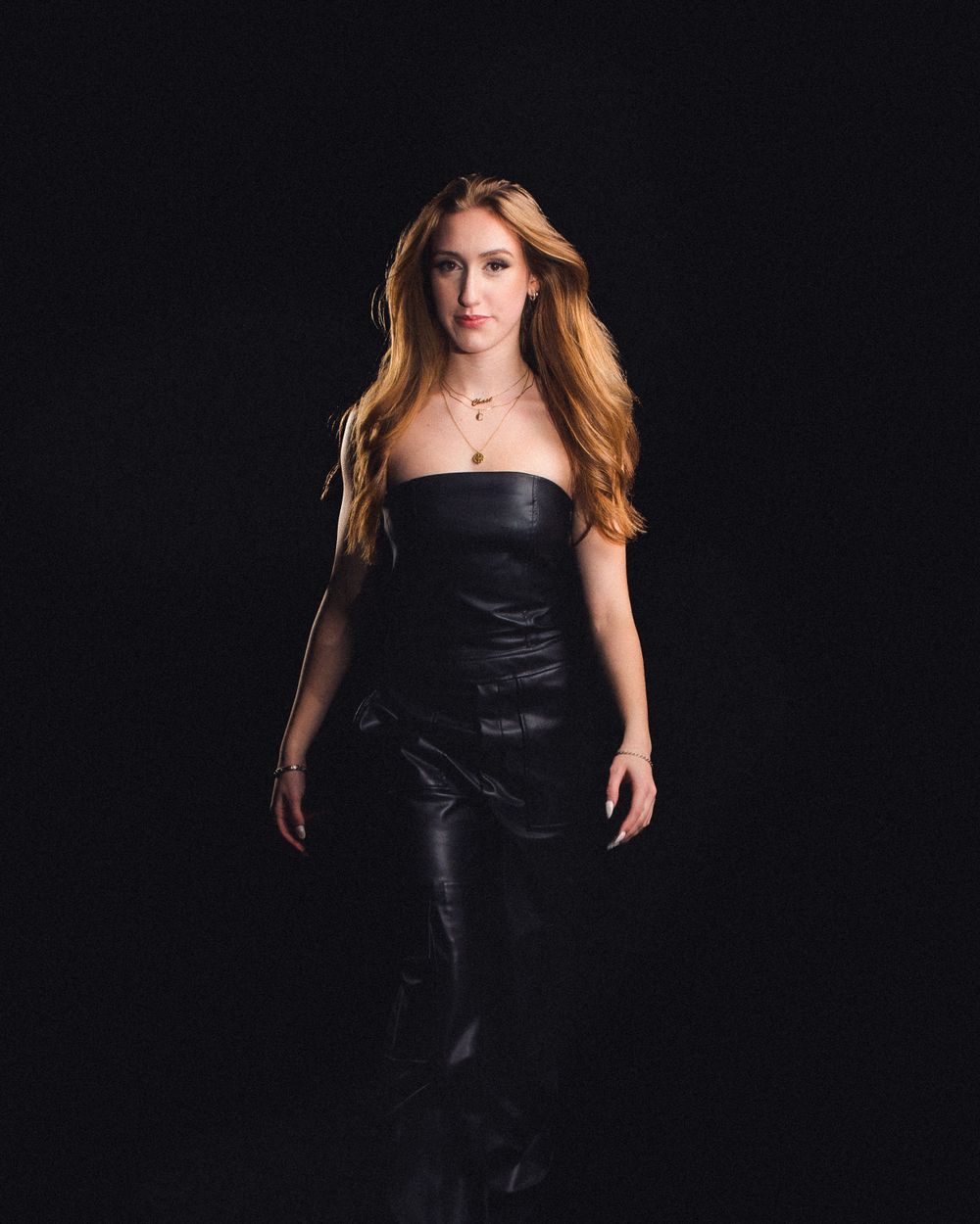 Fashion portrait of model in black leather dress against dark background.