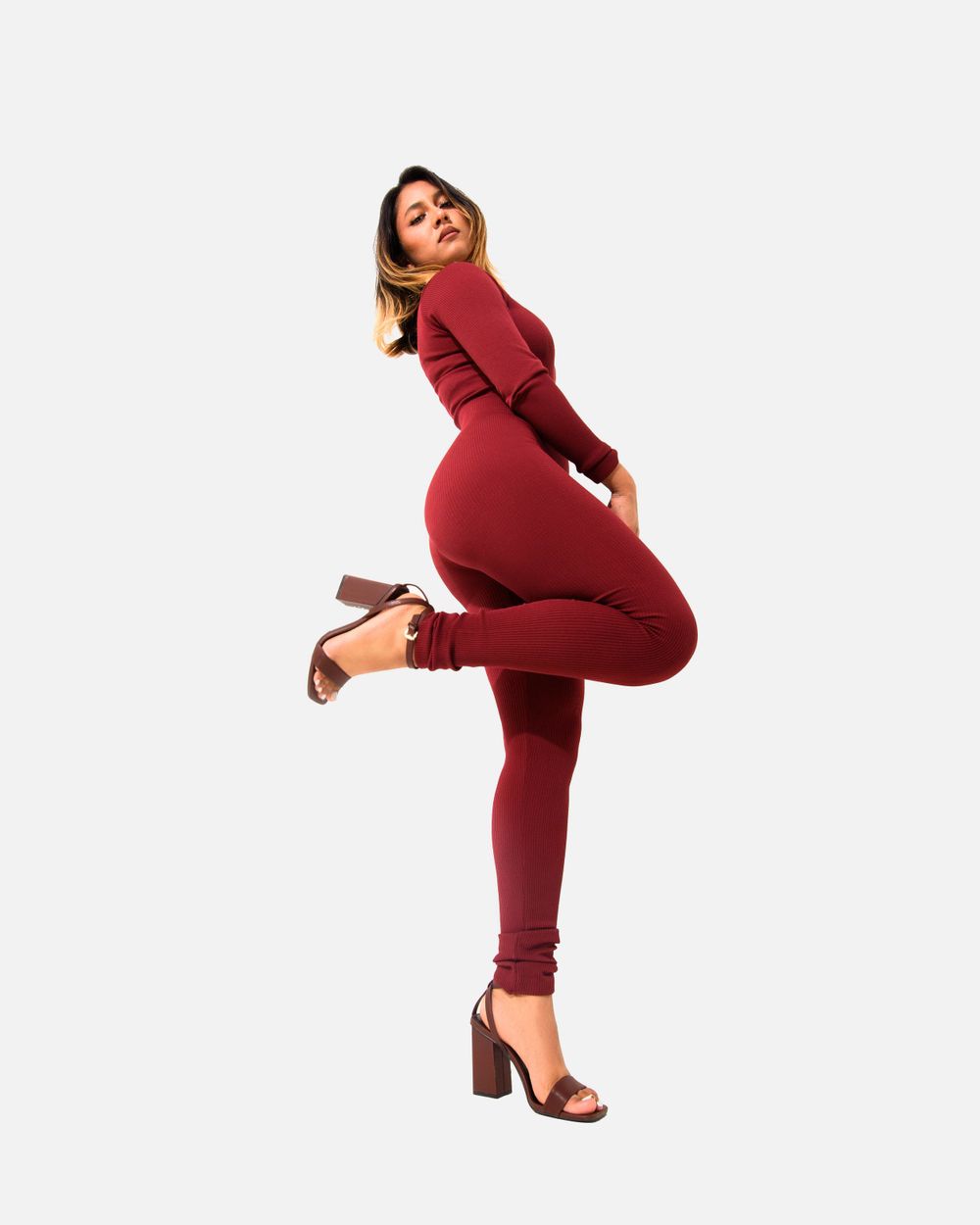 Stylish burgundy bodycon jumpsuit with heels against white background.