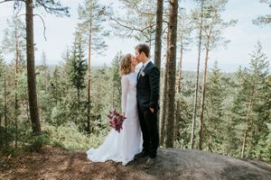 Brudepar fotografert i skogen. Det er høye trestammer og utsikt.