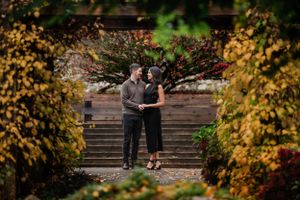 Romantic autumn engagement photo through natural garden frame.