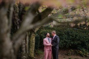A couple shares an intimate moment in a garden setting with soft focus foliage.