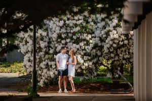 Couple standing together against blooming white magnolia trees in spring.