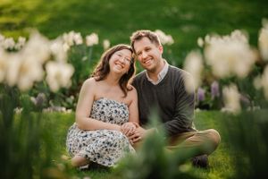 A couple sits together in a blooming garden with soft bokeh and natural lighting during golden hour outdoors.