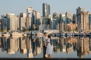 Downtown Vancouver skyline reflects in calm harbor waters with boats and modern skyscrapers at sunset.