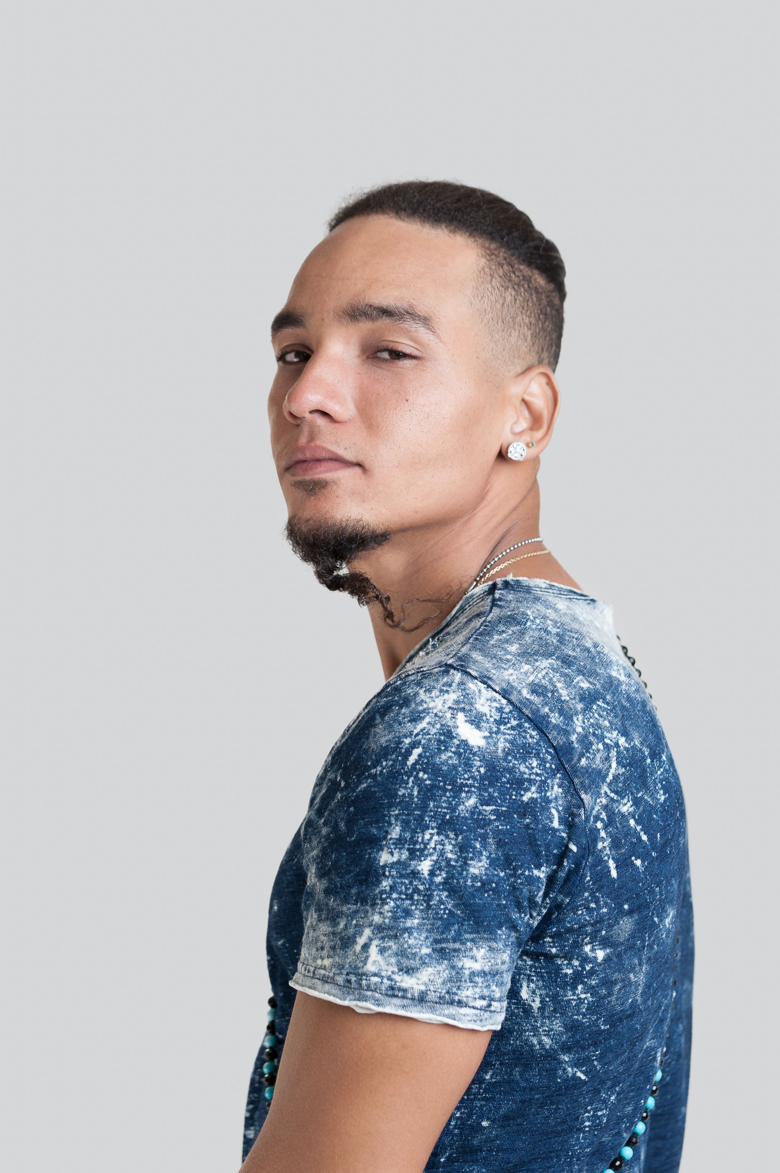Profile portrait of someone looking sideways wearing a distressed denim t-shirt against a light gray background.