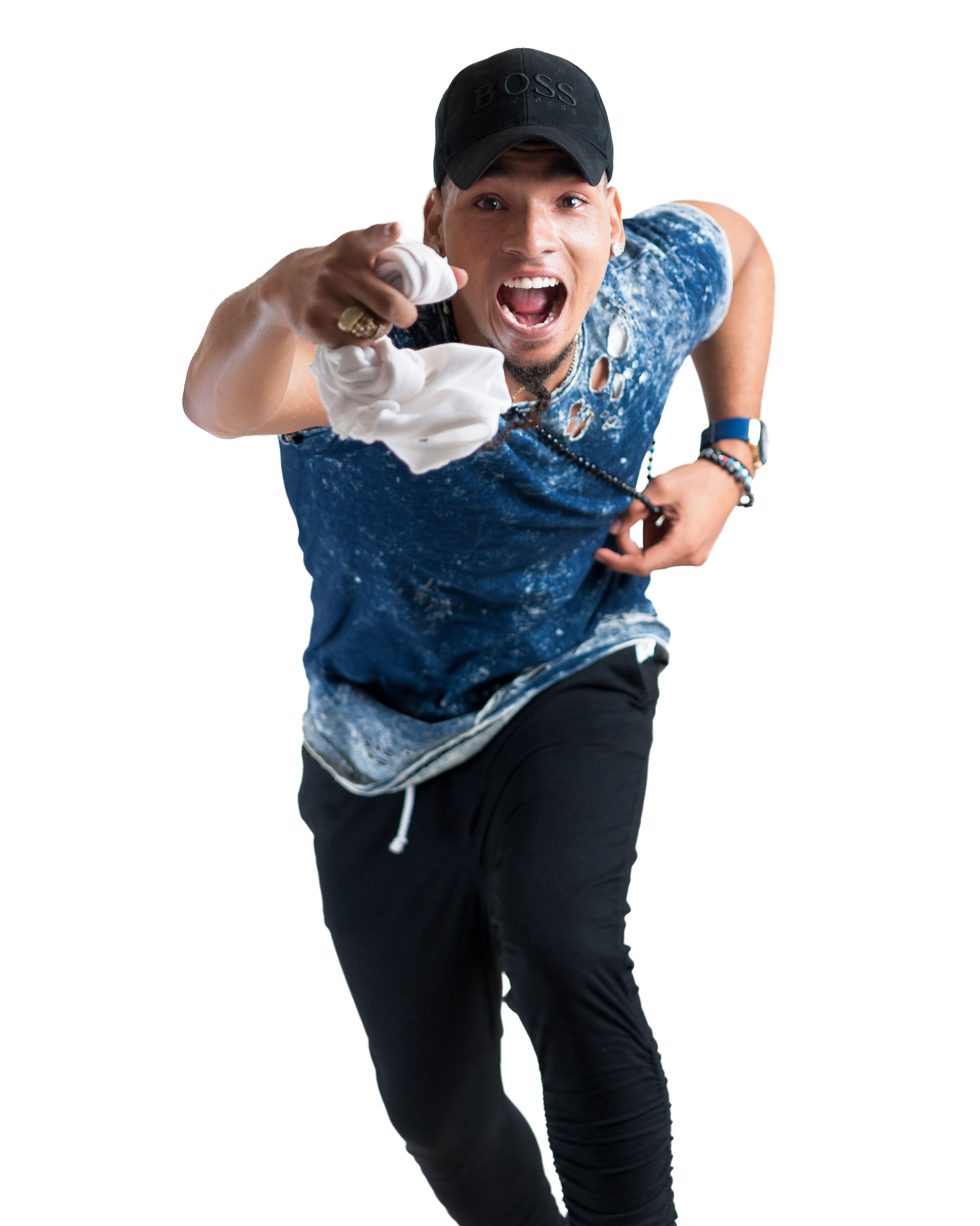 Energetic person wearing a blue tie-dye shirt and black baseball cap points at camera while striking dynamic pose.