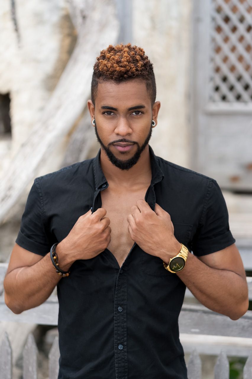 Stylish model in black button-down shirt with short sleeves poses while wearing gold watch and beard.