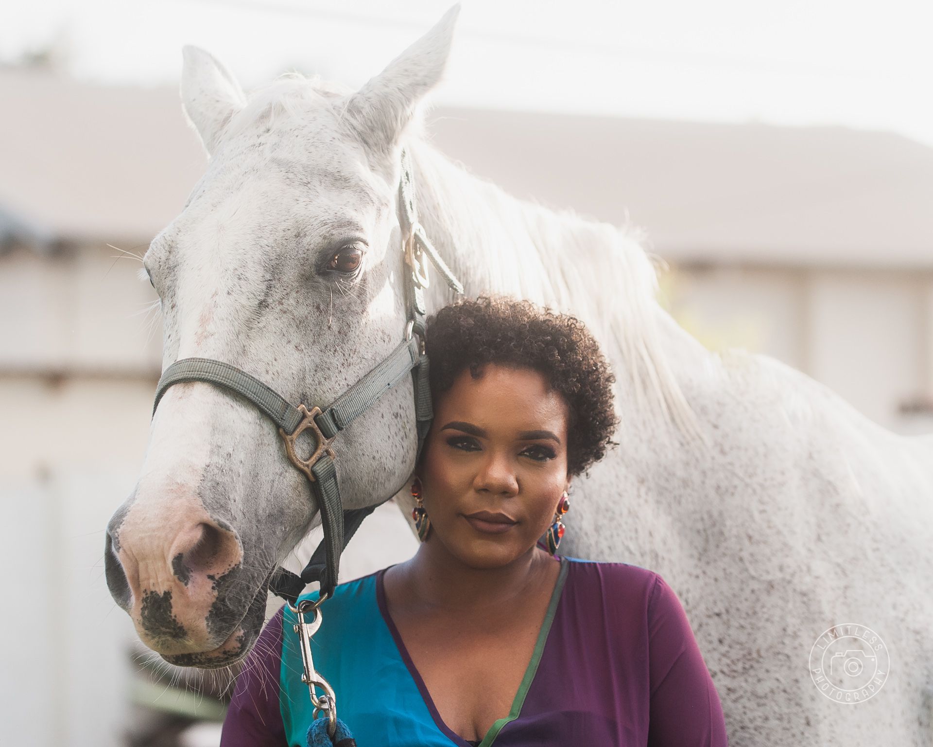 White horse and a person in a purple top pose together in a close-up portrait shot.