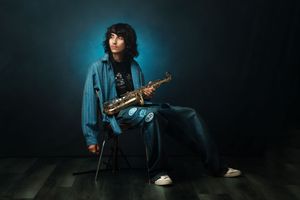 Musicians perform in moody lighting holding electric guitars and performing on stage with atmospheric blue lighting.