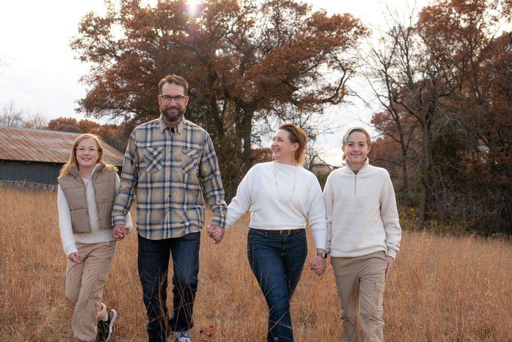 Photo of a family walking together through an autumn field during golden hour sunset.