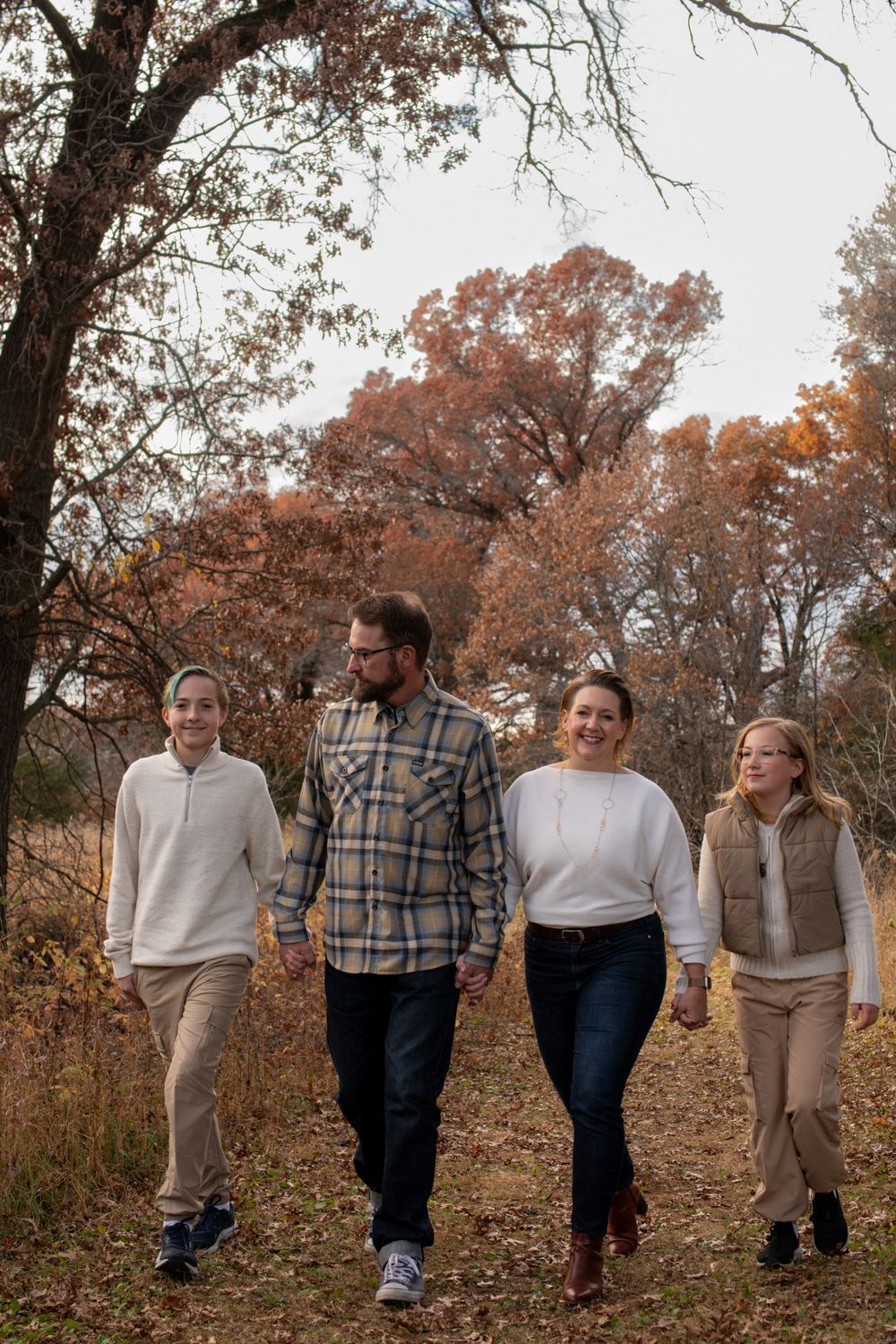 A family walking together on an autumn path surrounded by colorful fall foliage.