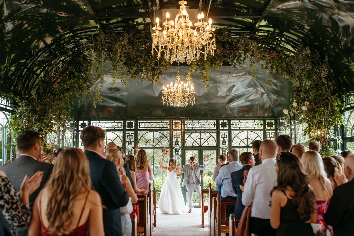 An elegant wedding reception venue decorated with chandeliers and greenery.