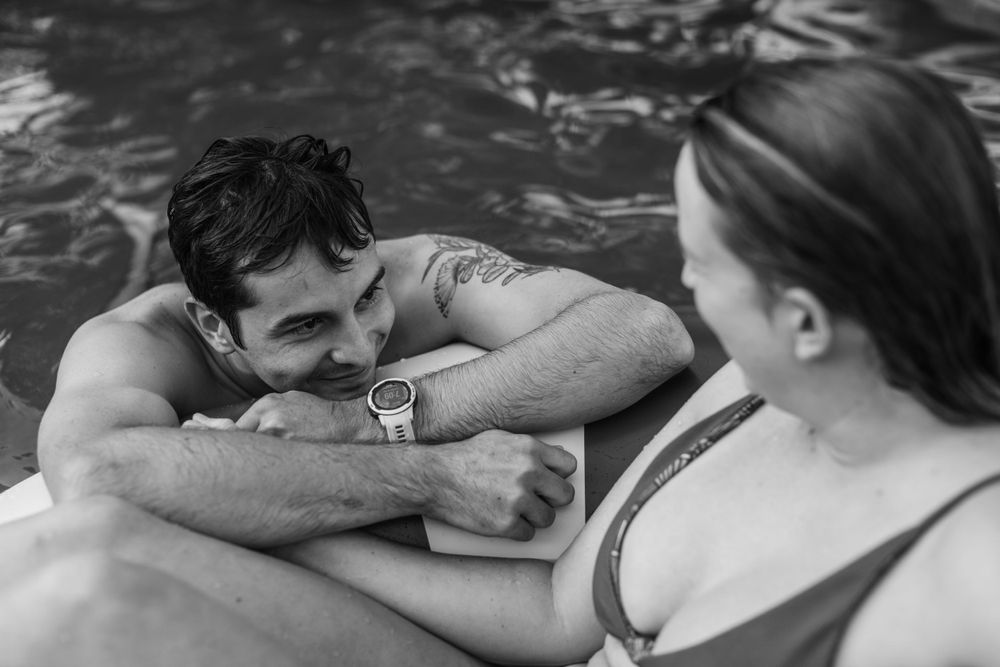 Black and white photo of couple sharing tender moment on pool float.