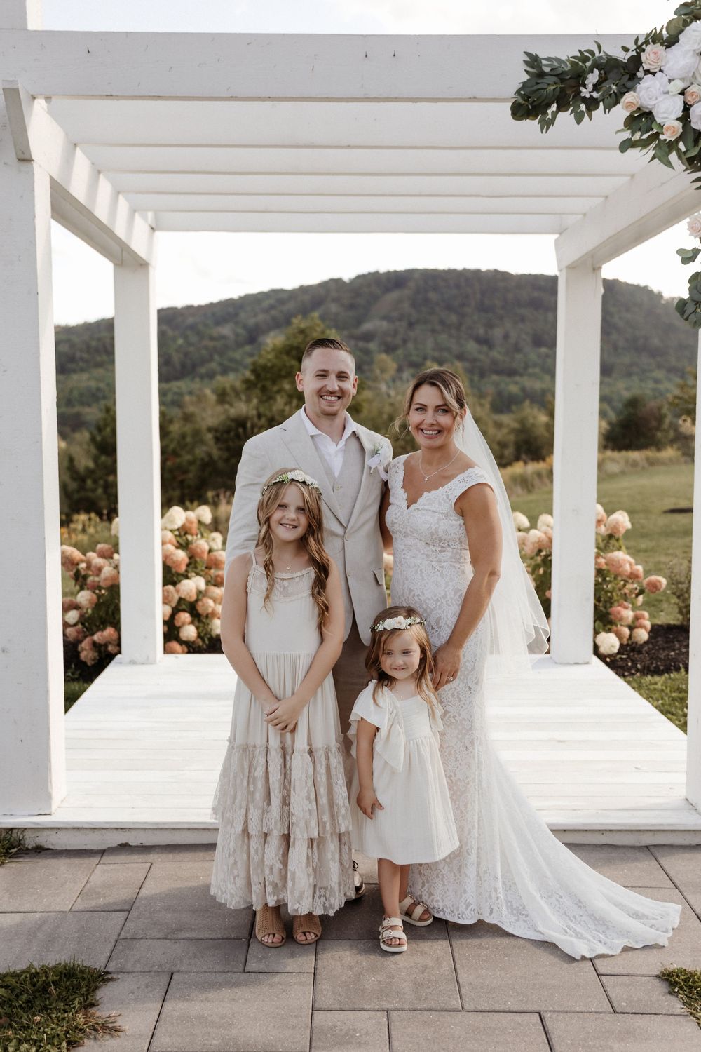 An elegant outdoor wedding scene with white columns and scenic mountain views in the background.