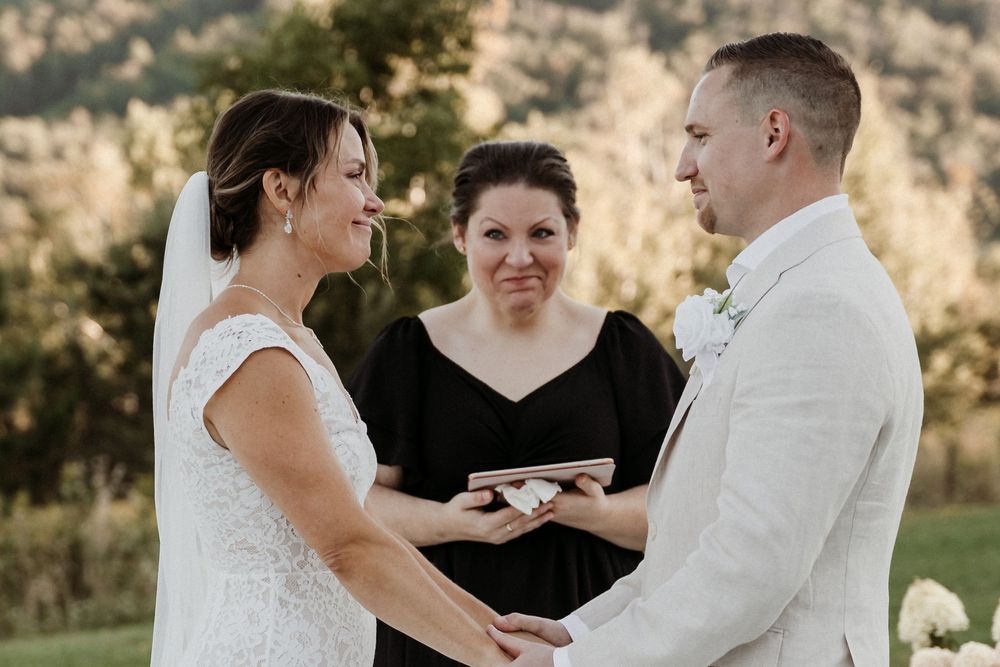 An intimate outdoor wedding ceremony with a couple exchanging rings in front of an officiant during golden hour.