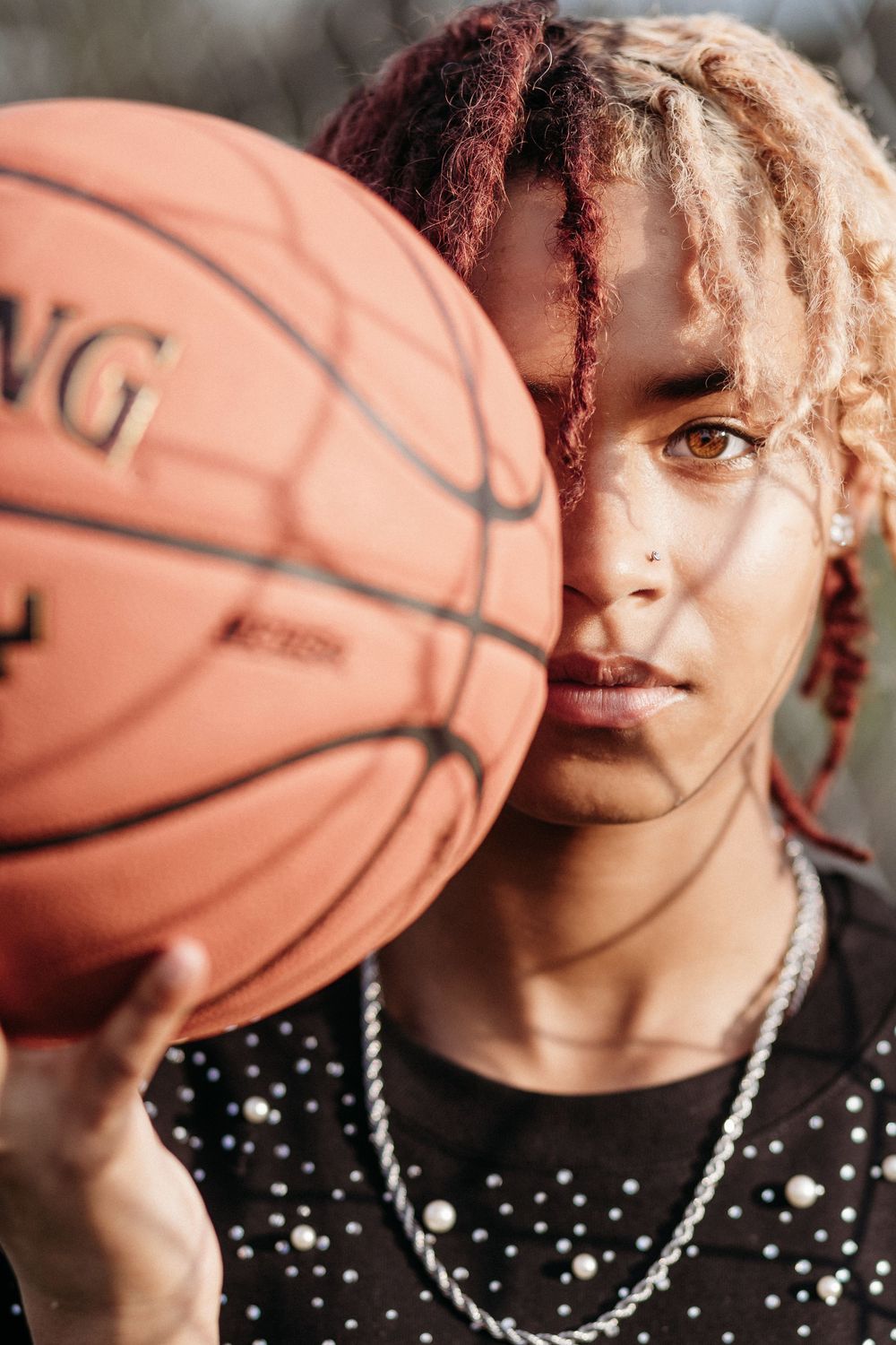 A series of close-up portraits showing a basketball player with curly red hair and a polka dot shirt holding a basketball.